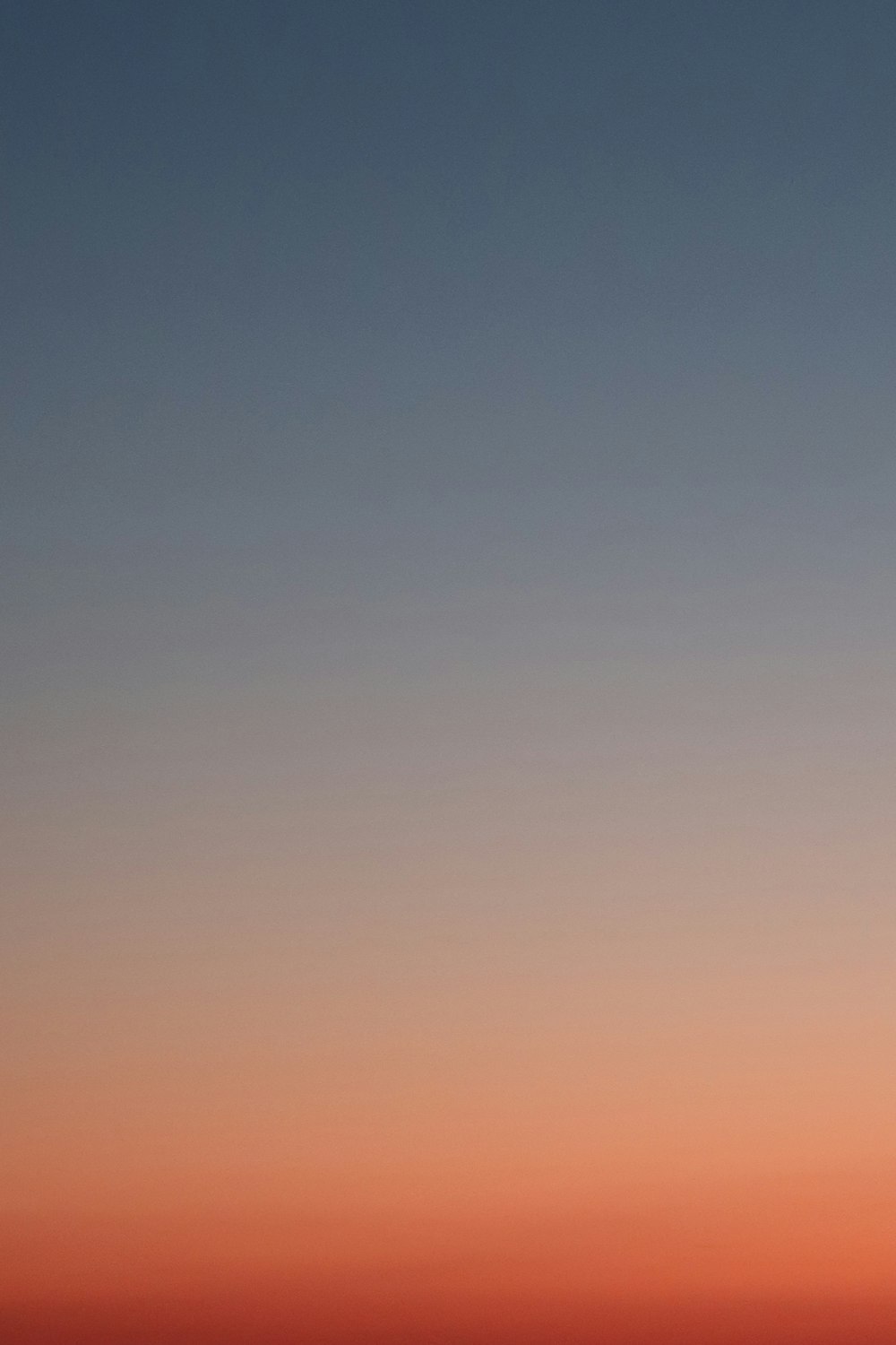 a plane flying in the sky at sunset