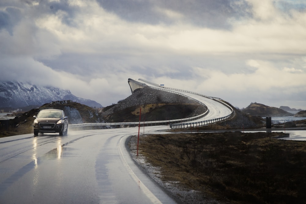 a car driving down a wet road with mountains in the background