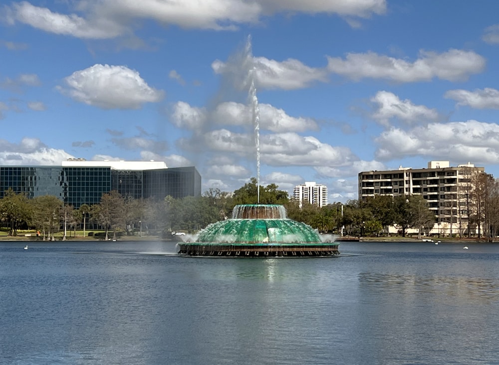 a large green fountain in the middle of a lake