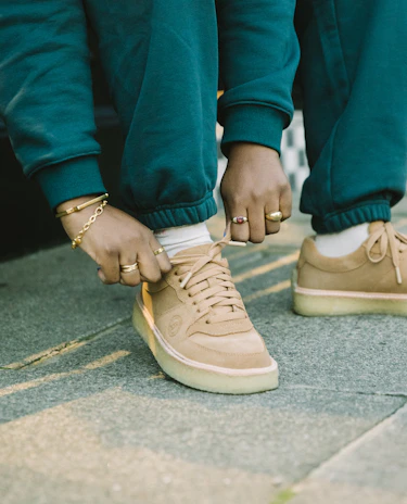 Someone tying the laces on eco-friendly sneakers paired with Gratitude joggers.