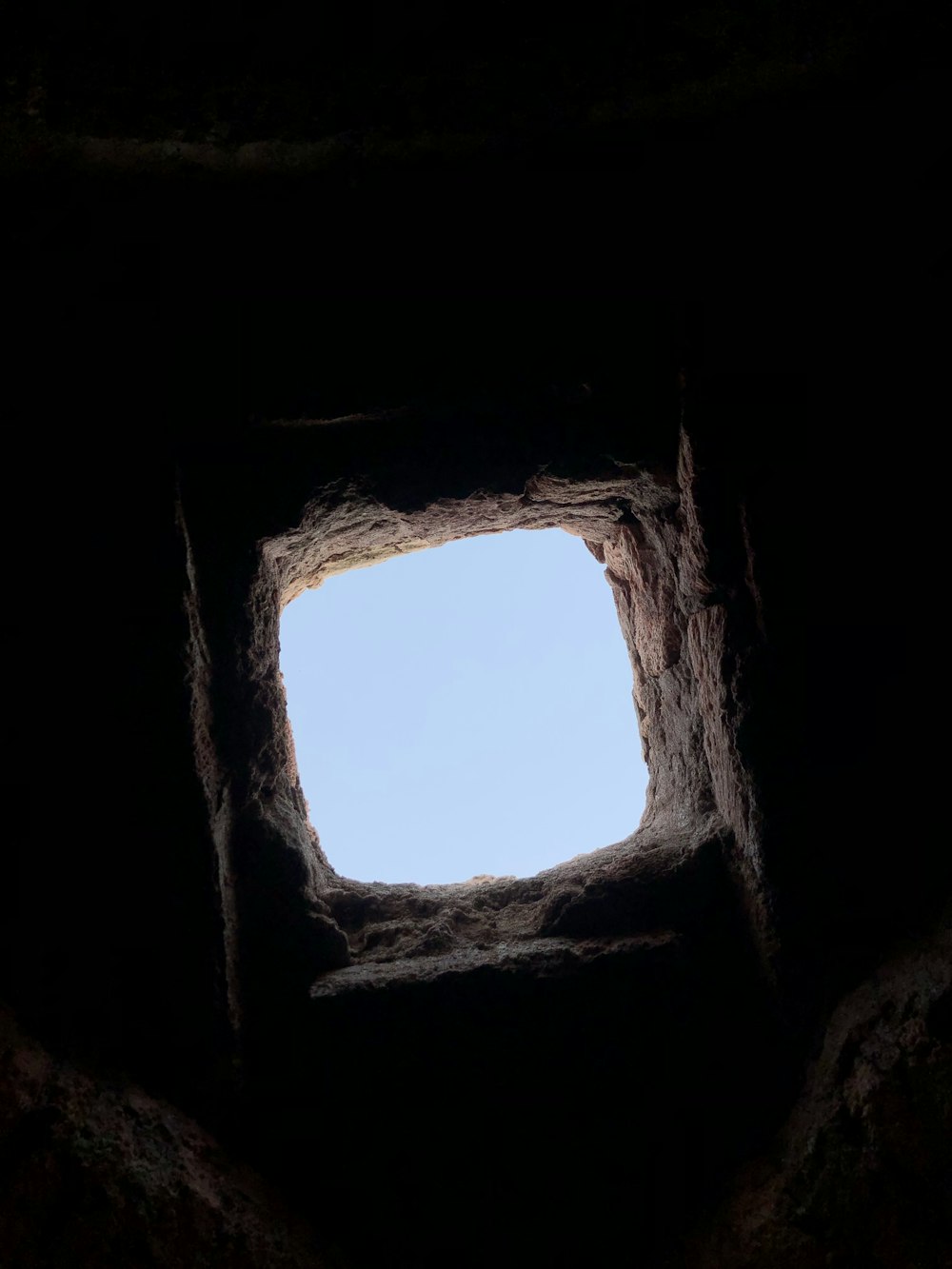 a view of the sky through a window in a cave