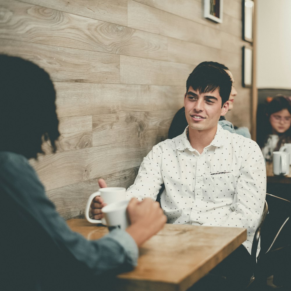 a man sitting at a table with a cup of coffee