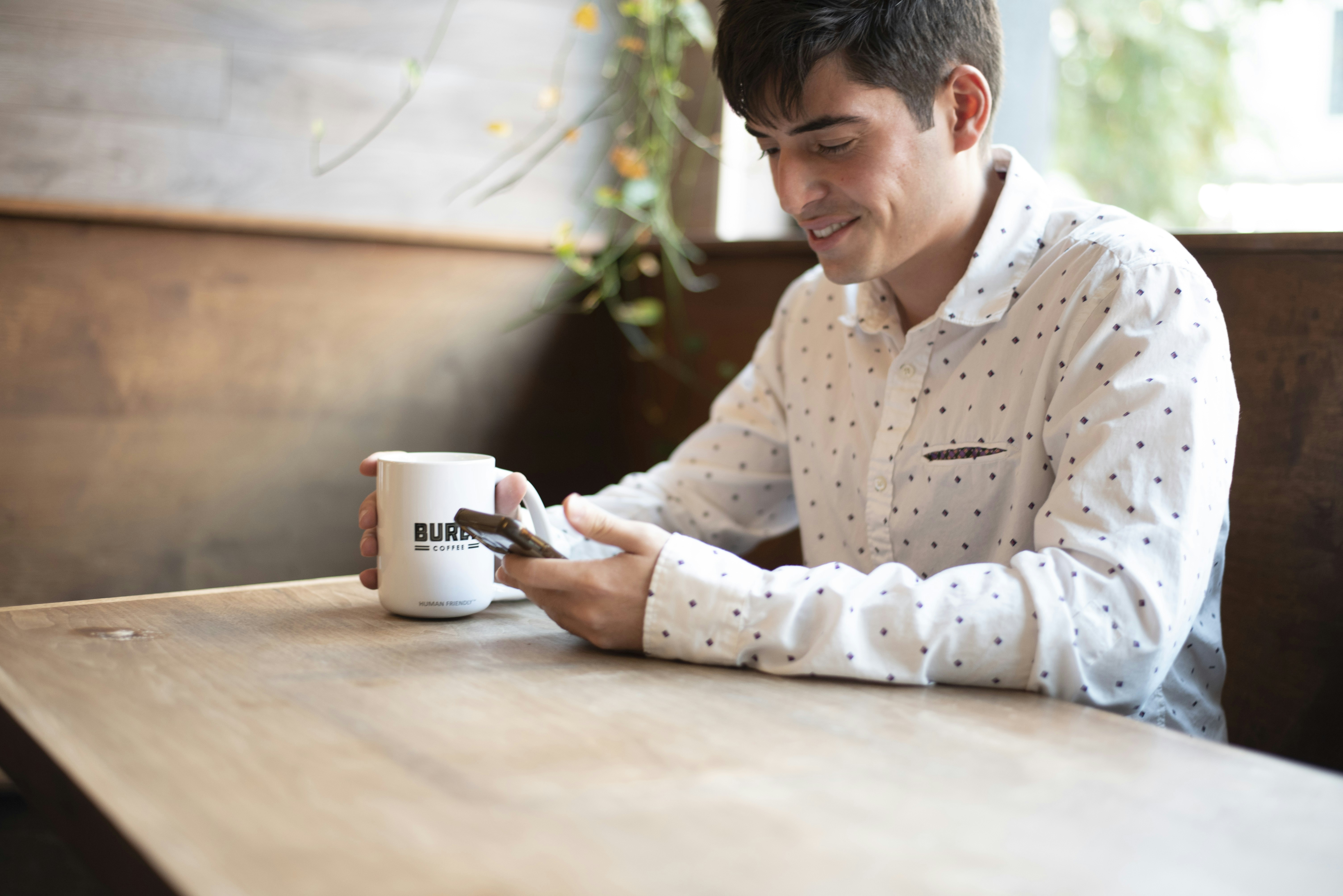 person sitting at coffee shop table using smartphone stylus to solve puzzle