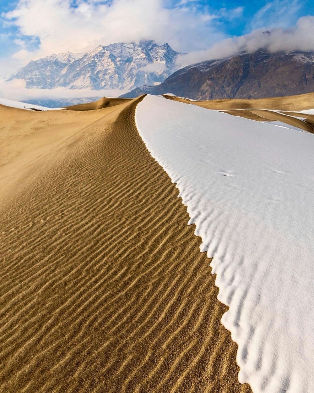 a large sand dune with a mountain in the background