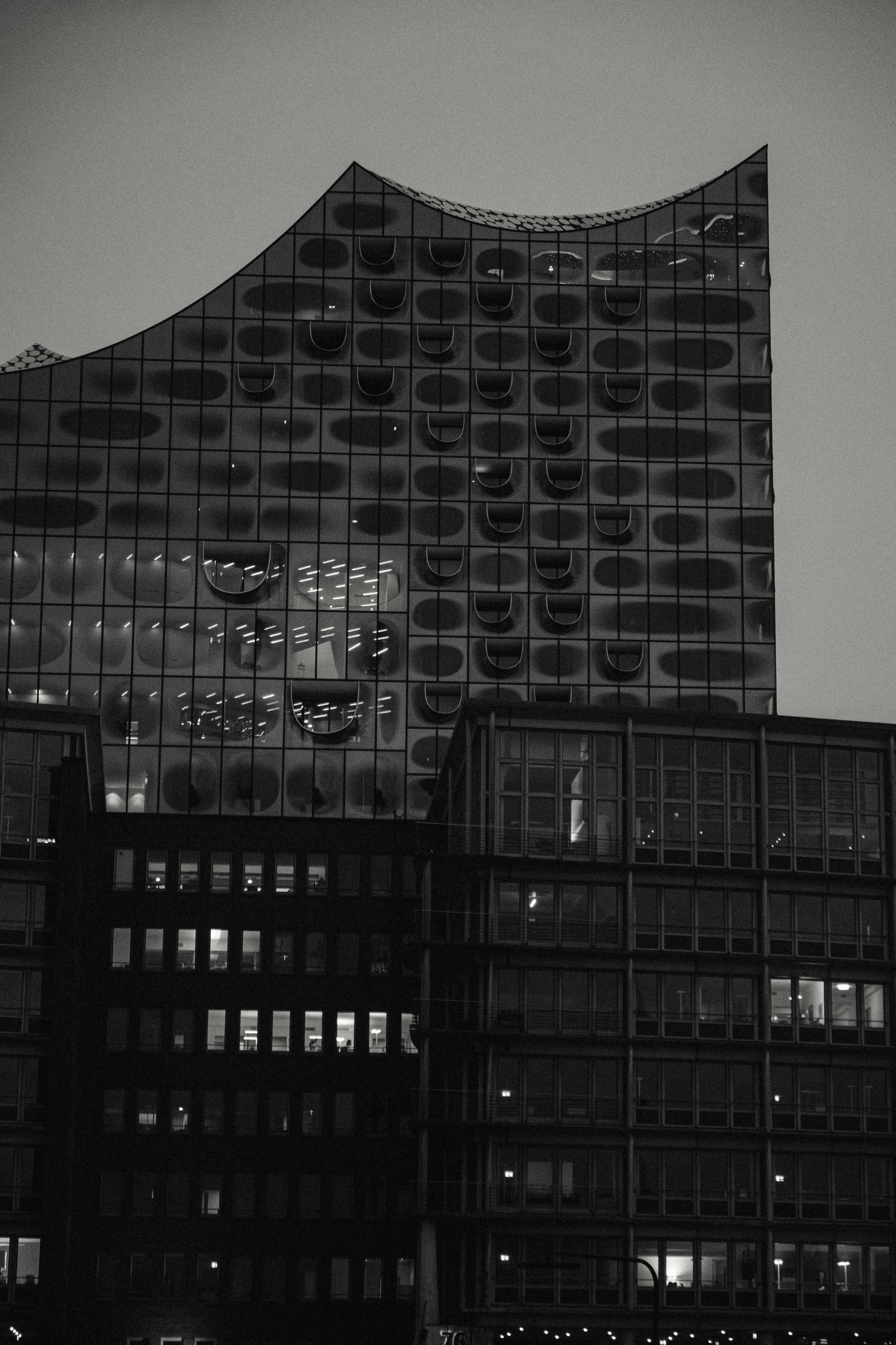 Contemporary glass office building facade at dusk with illuminated interior and geometric steel structure