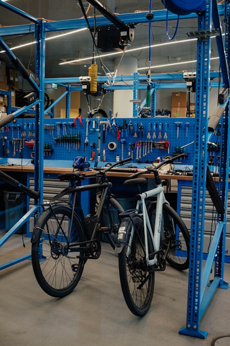Duas bicicletas em uma oficina de loja com painel azul cheio de ferramentas de manutenção
