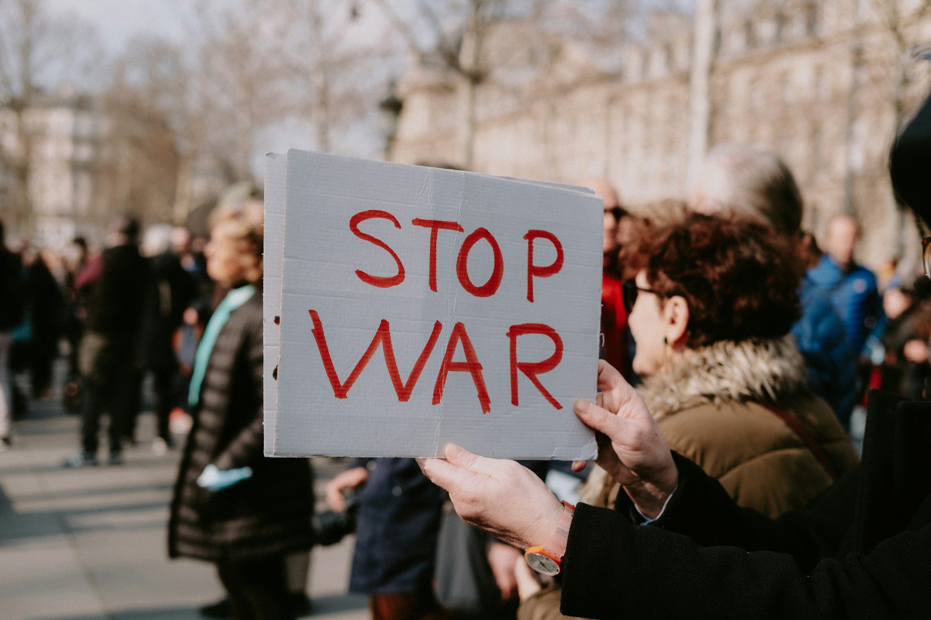 a woman holding a sign that says stop war