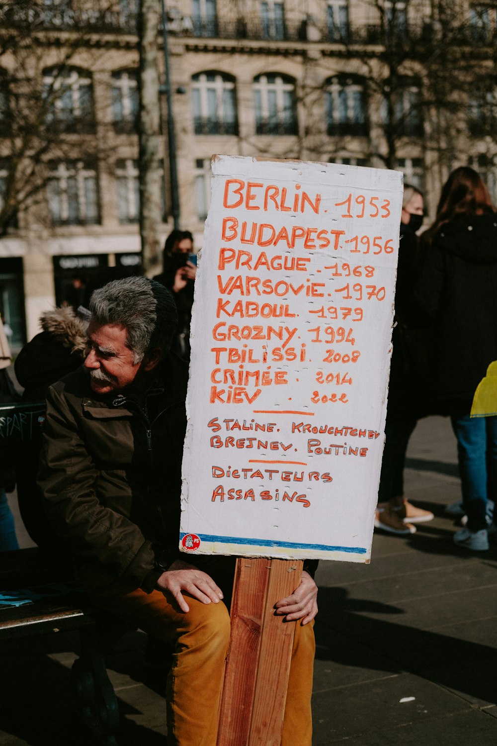 a man sitting on a bench holding a sign