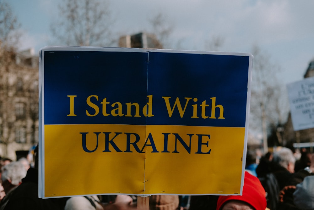 a person holding a sign that says i stand with ukraine