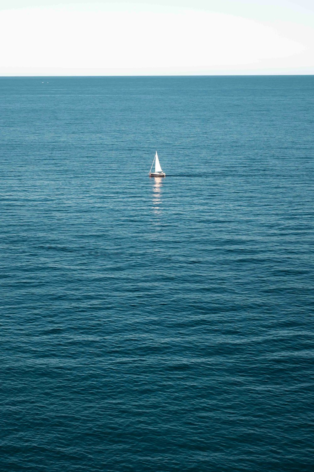 a lone sailboat in the middle of the ocean