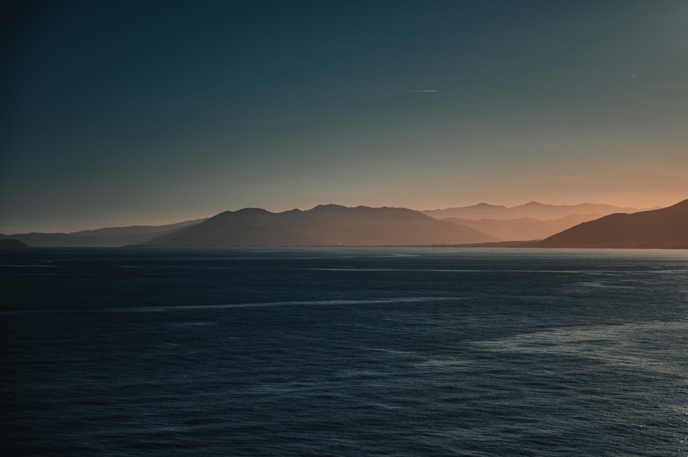 a large body of water with mountains in the background