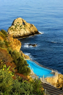 a swimming pool on the side of a cliff next to the ocean