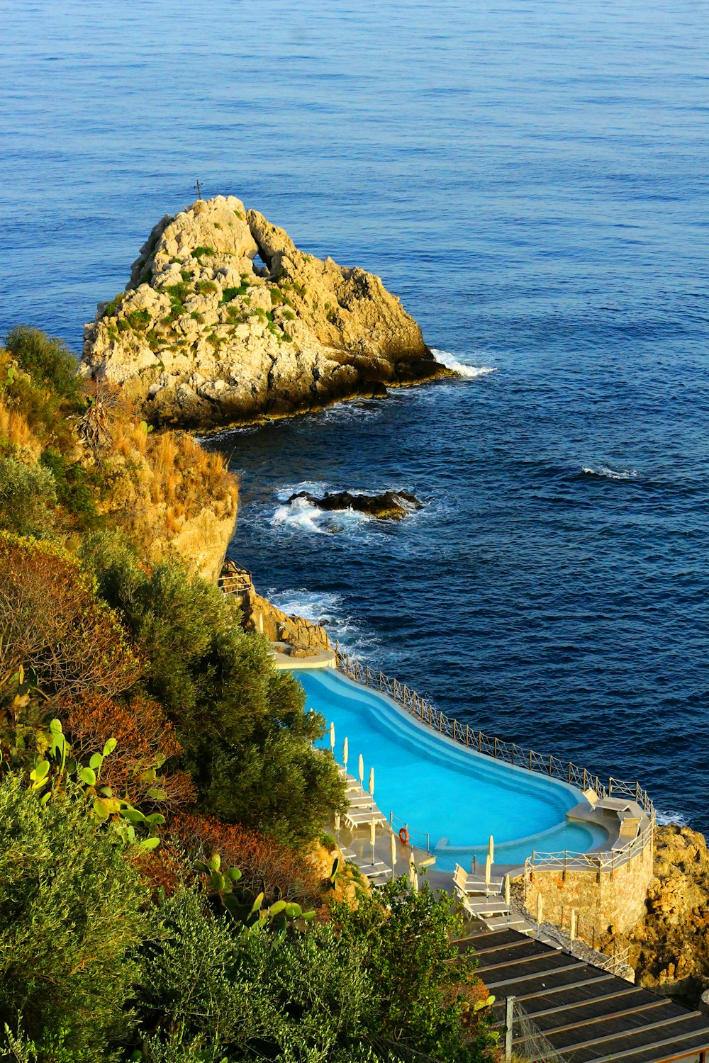 a swimming pool on the side of a cliff next to the ocean