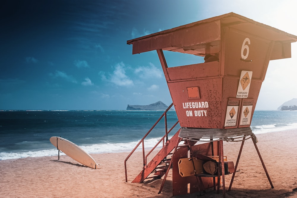 a lifeguard stand on the beach with a surfboard