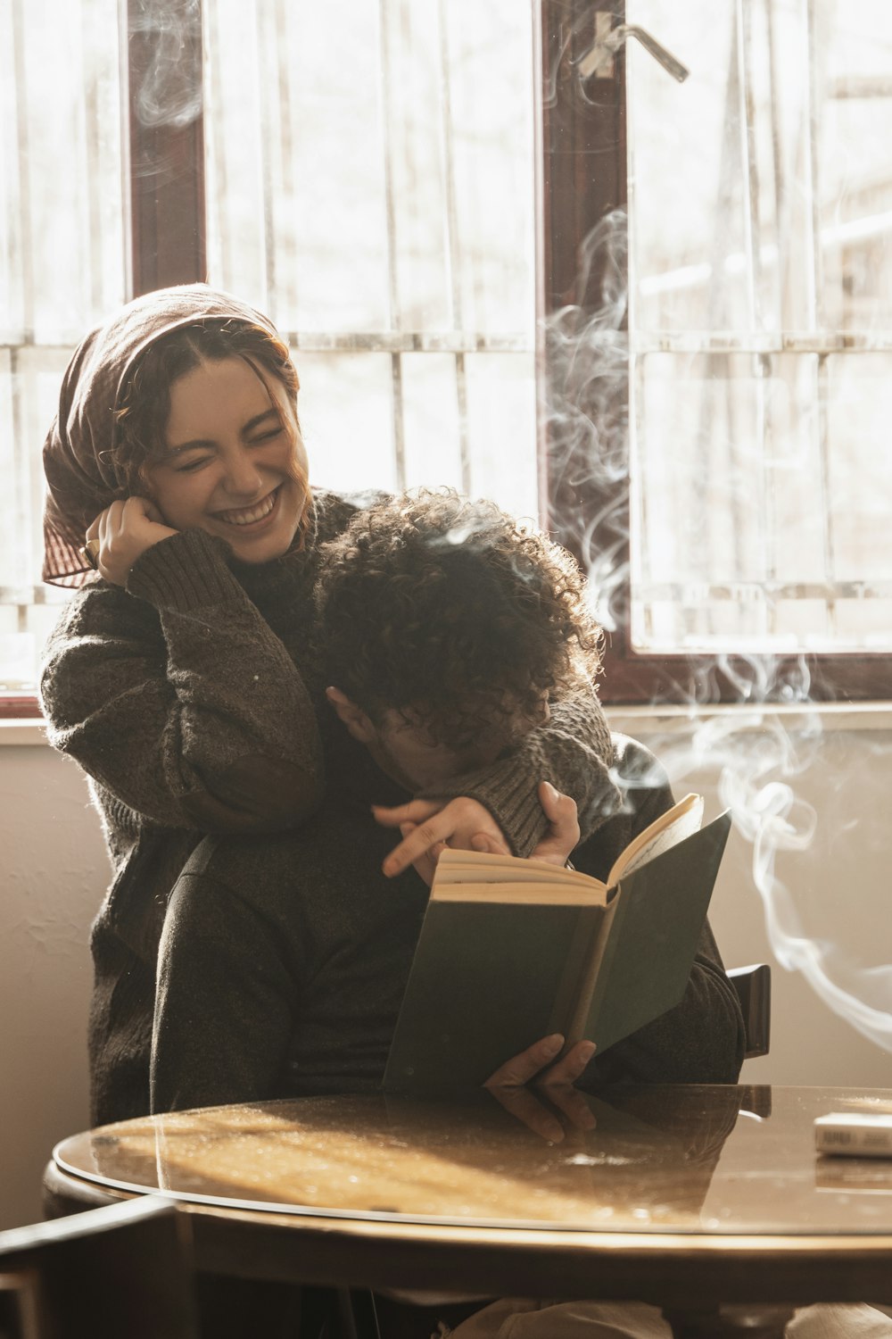 a woman hugging a man who is reading a book