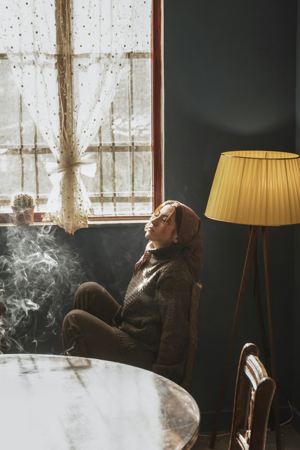 a woman sitting at a table smoking a cigarette