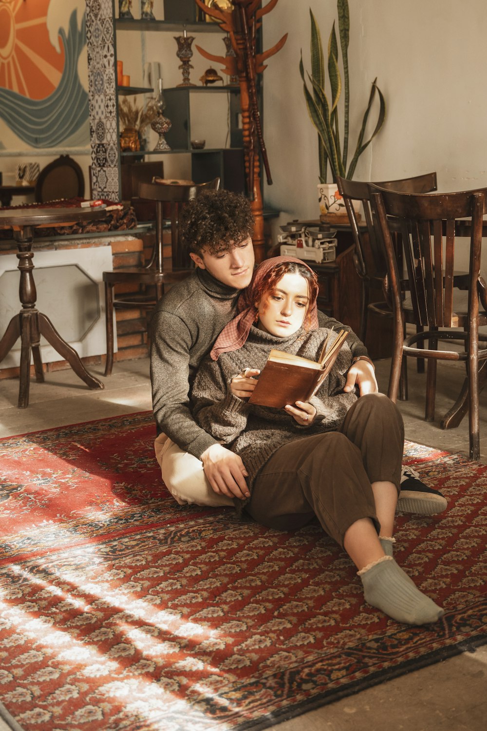 a man and woman sitting on a rug reading a book