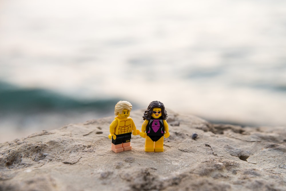a couple of legos standing on top of a rock