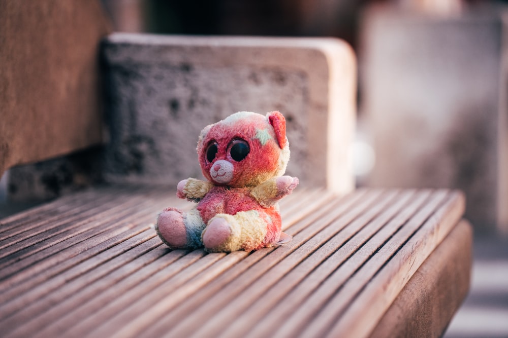 a small stuffed animal sitting on top of a wooden bench