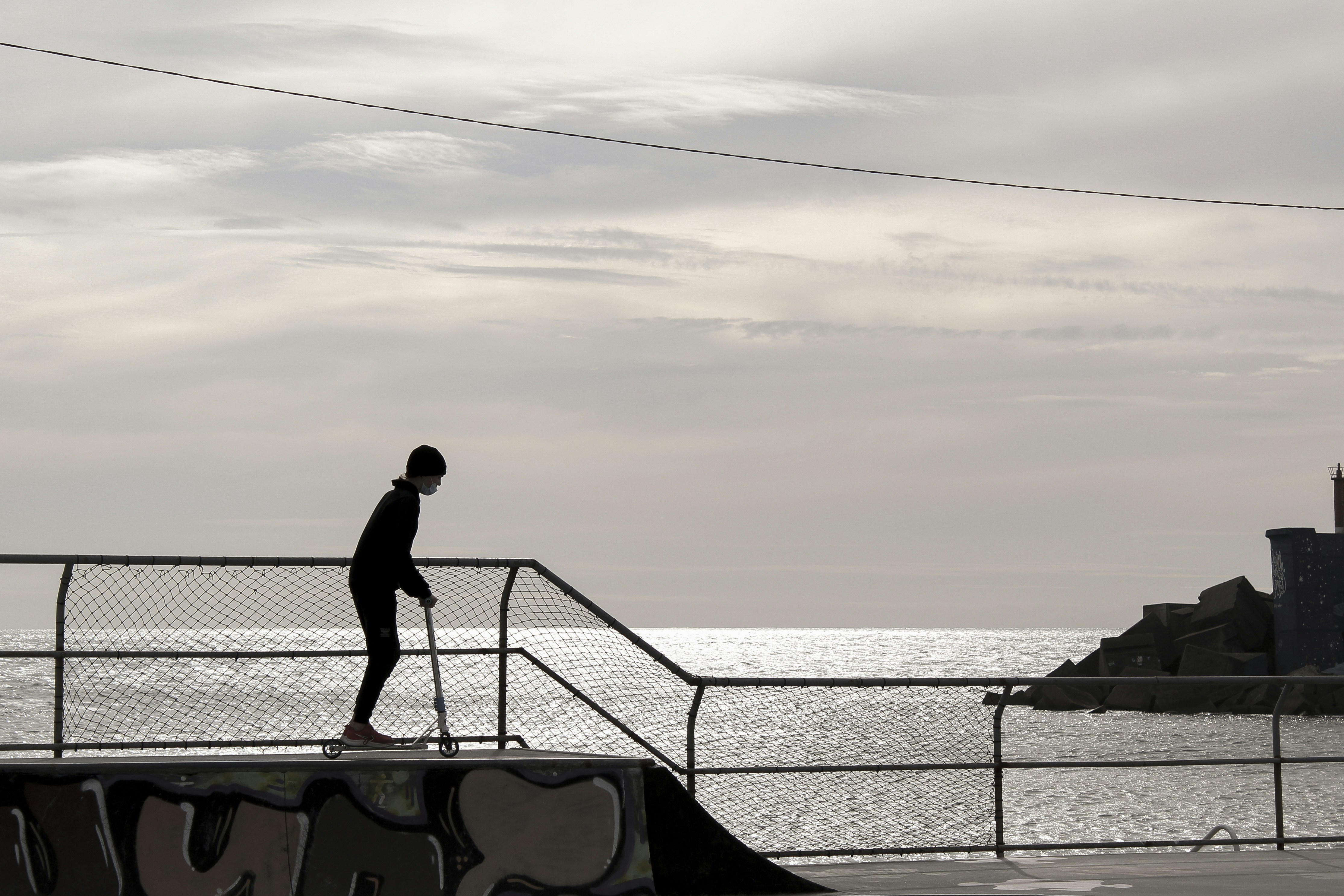a man riding a skateboard down a rail next to the ocean