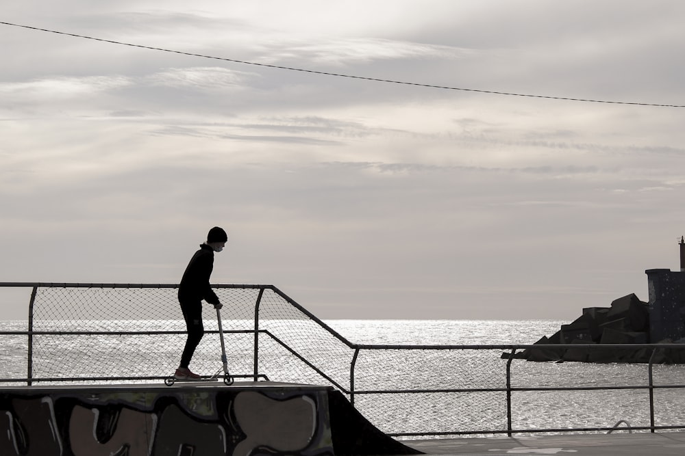 a man riding a skateboard down a rail next to the ocean