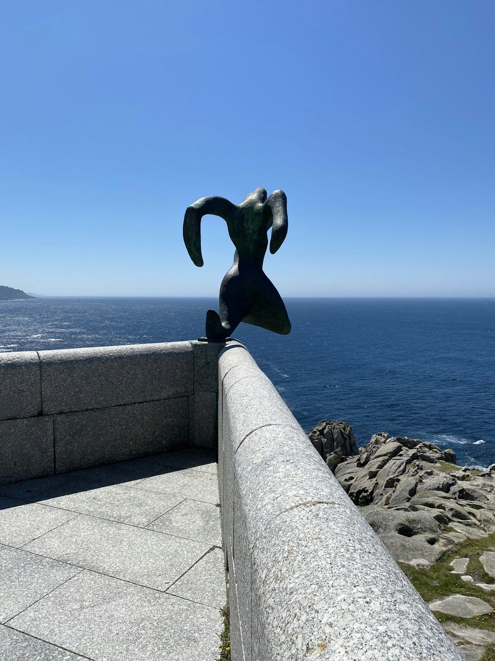 a statue of a man on a ledge near the ocean