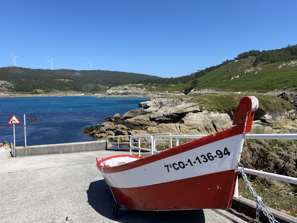 a red and white boat sitting on the side of a road