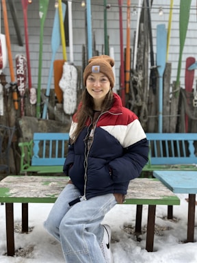 A cozy winter outfit laid out beside sports gear on a wooden bench