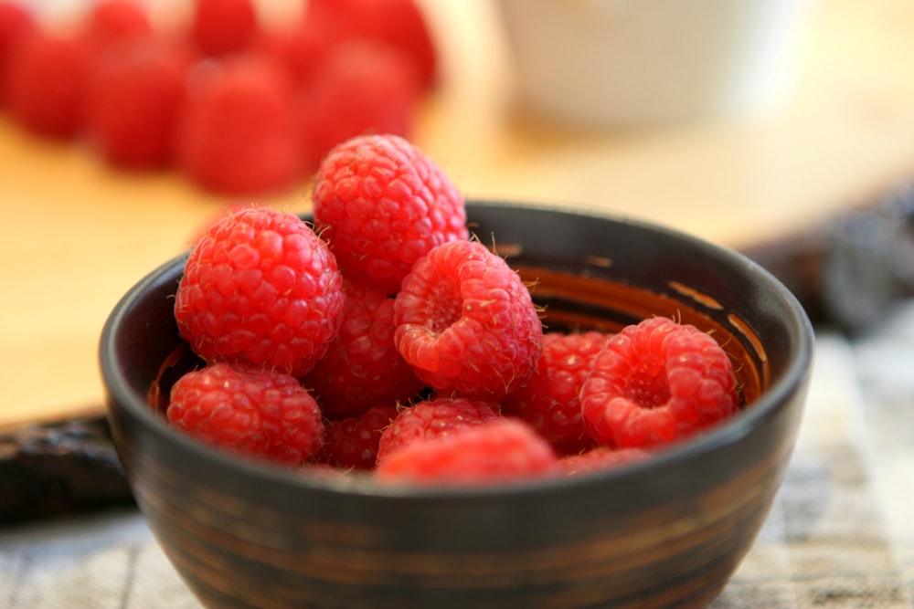 a bowl of raspberries sitting on a table