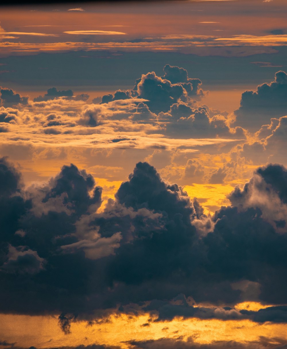 a plane flying through a cloudy sky at sunset