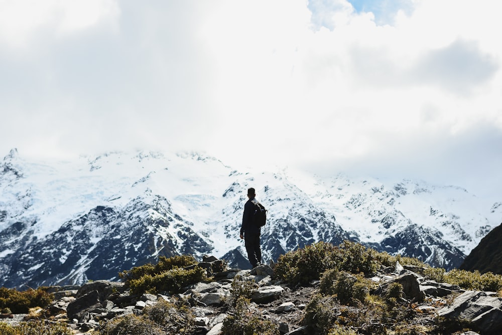 um homem de pé no topo de uma montanha rochosa