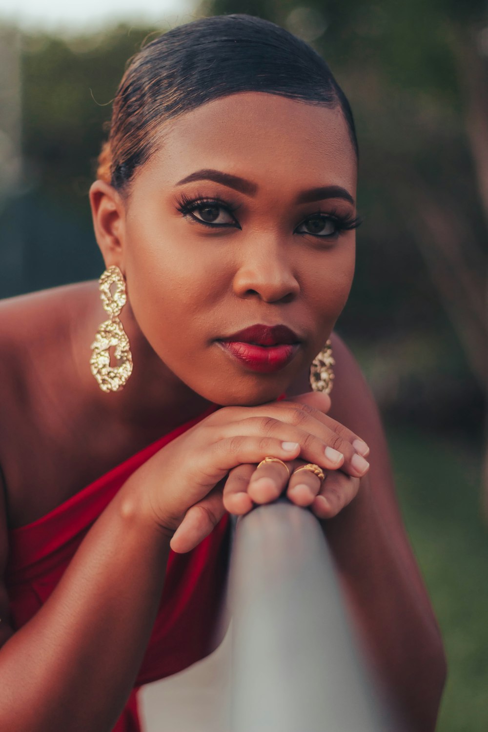 a woman in a red dress leaning on a rail