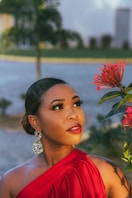 a woman in a red dress standing next to a flower