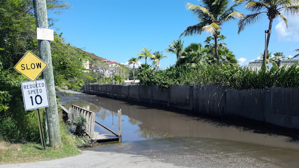 a flooded street next to a wooden fence