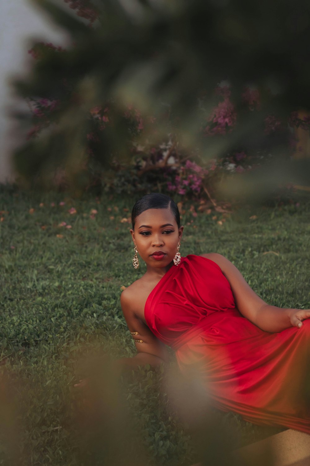 a woman in a red dress sitting in the grass