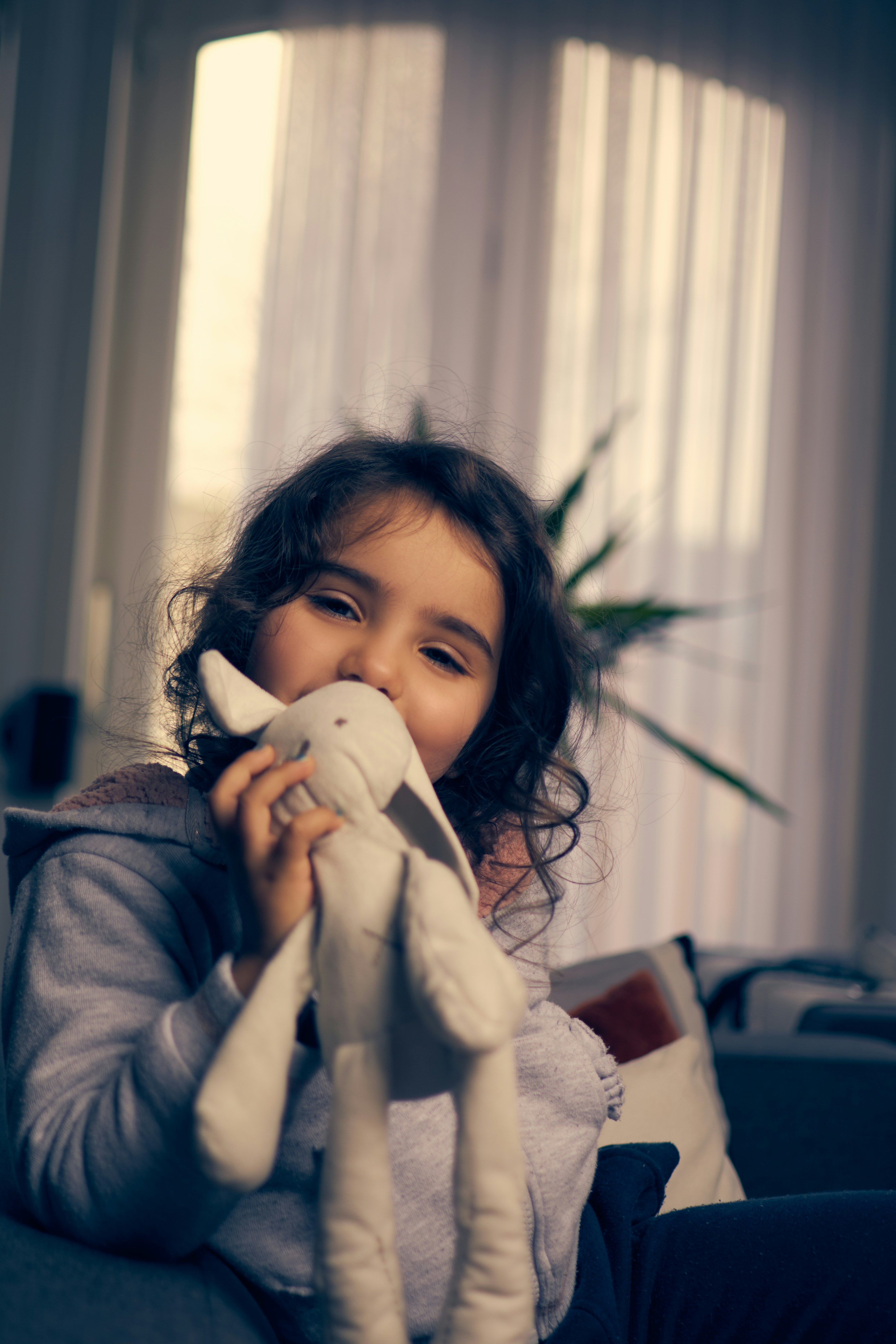 a little girl sitting on a couch holding a stuffed animal