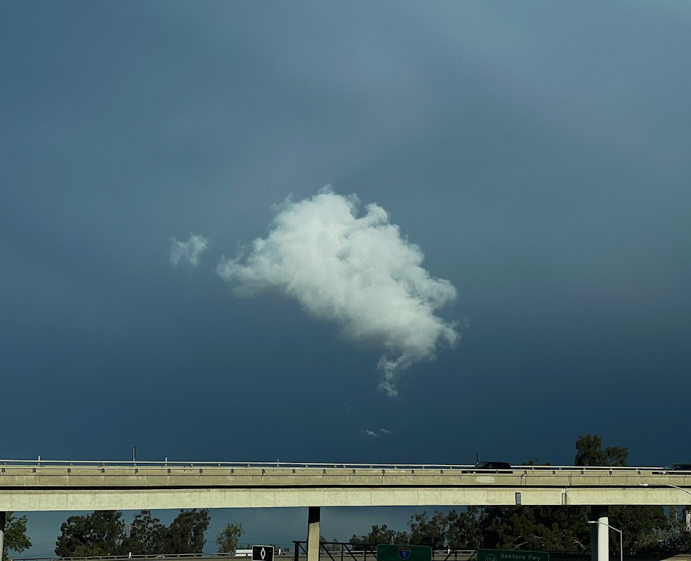 a cloud is floating over a highway under a cloudy sky