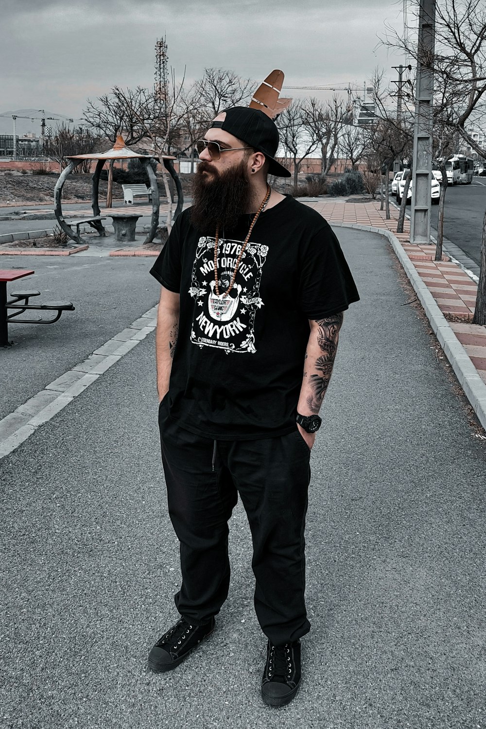 a man with a beard wearing a black shirt and black pants