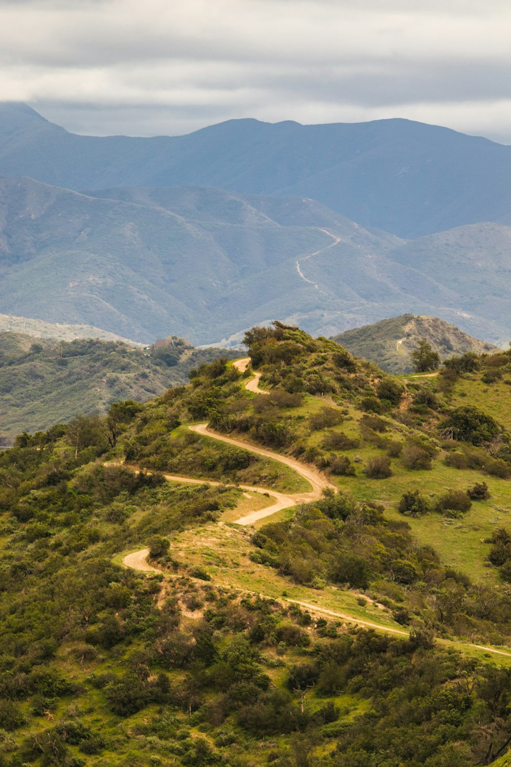 a dirt road winding through a lush green hillside