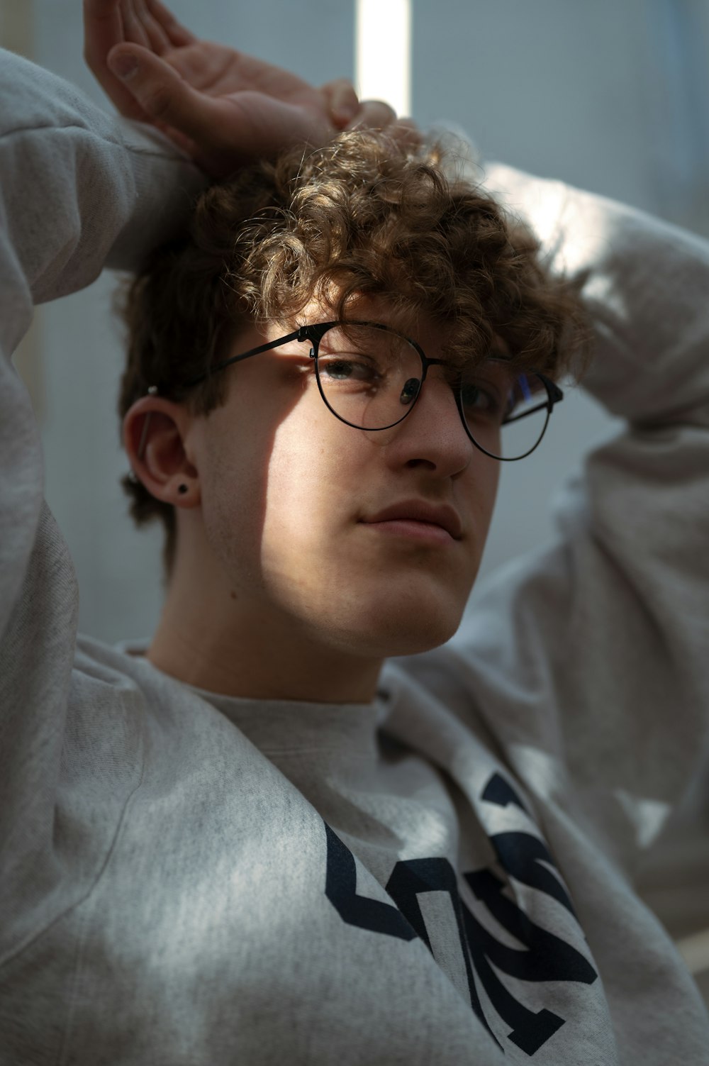 a young man with curly hair wearing glasses