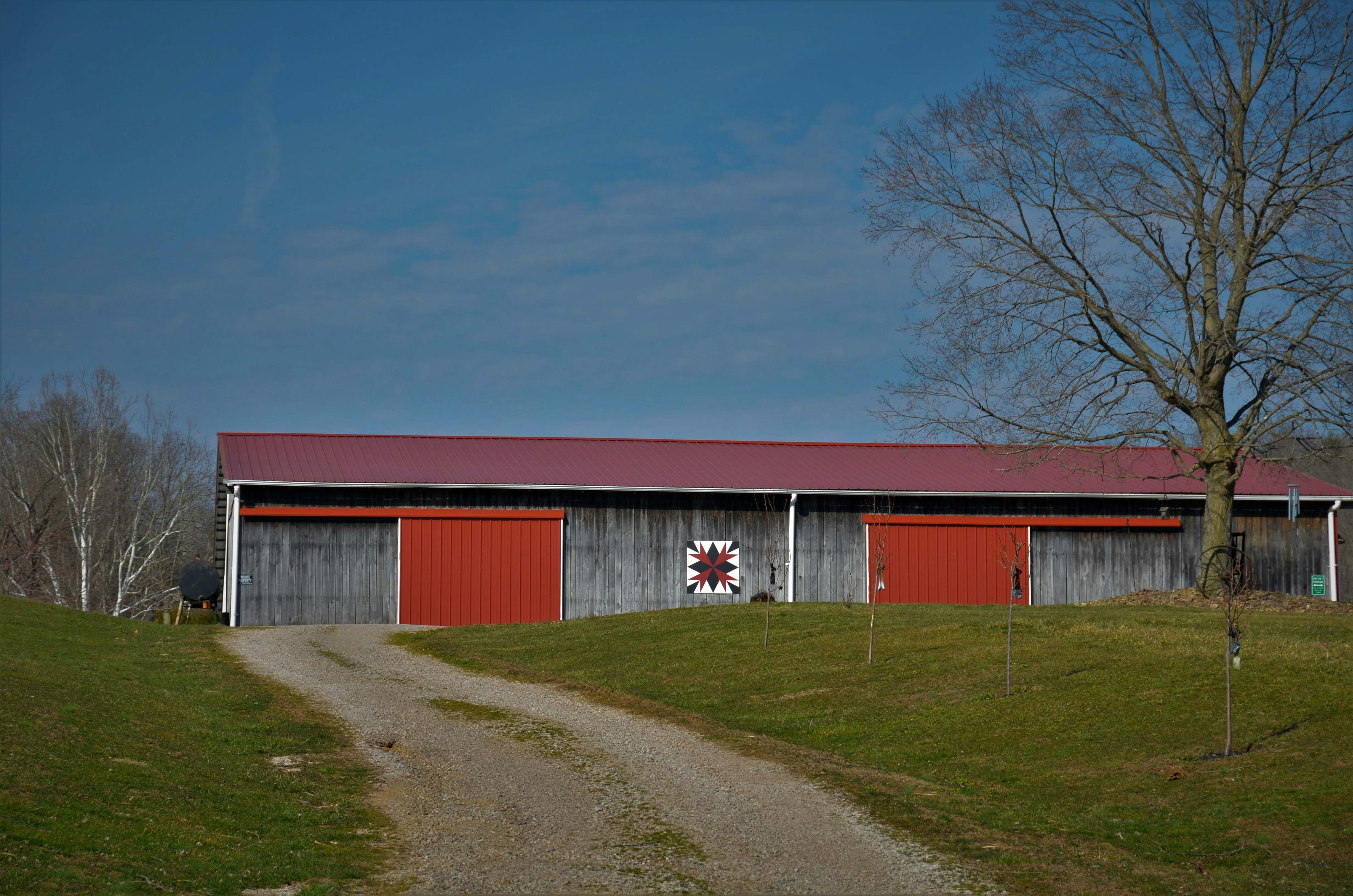 Faded long red and gray barn with barn quilt