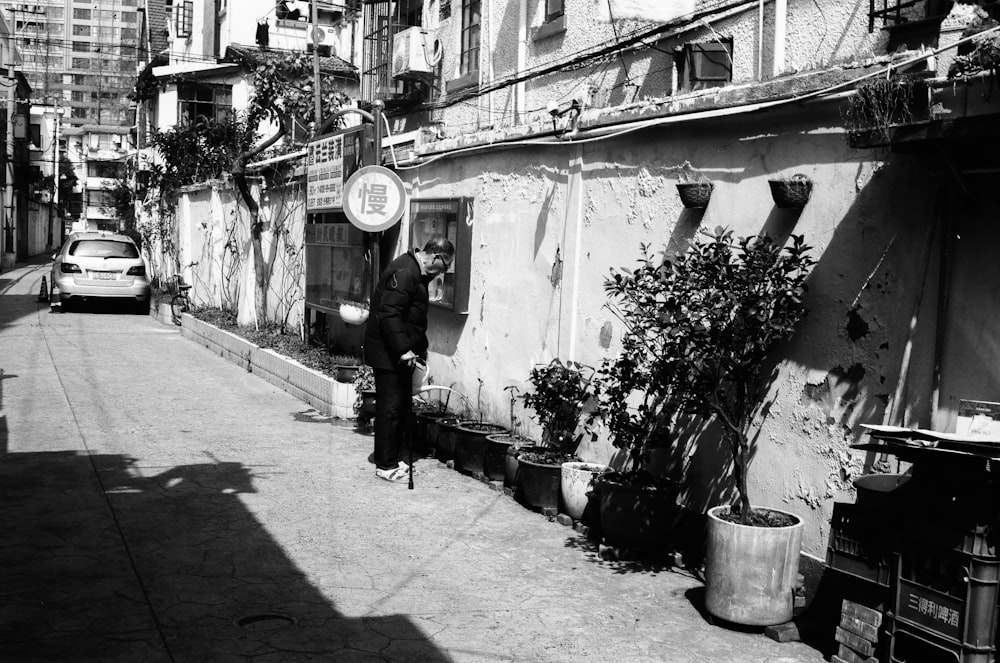 a black and white photo of a man standing outside of a building