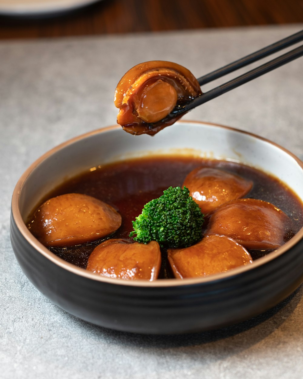 a bowl of soup with broccoli and chopsticks