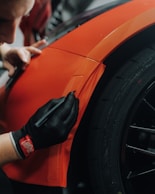a man is working on an orange car