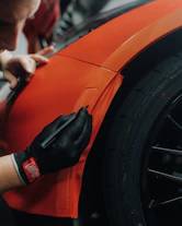 a man is working on an orange car