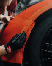 a man is working on an orange car