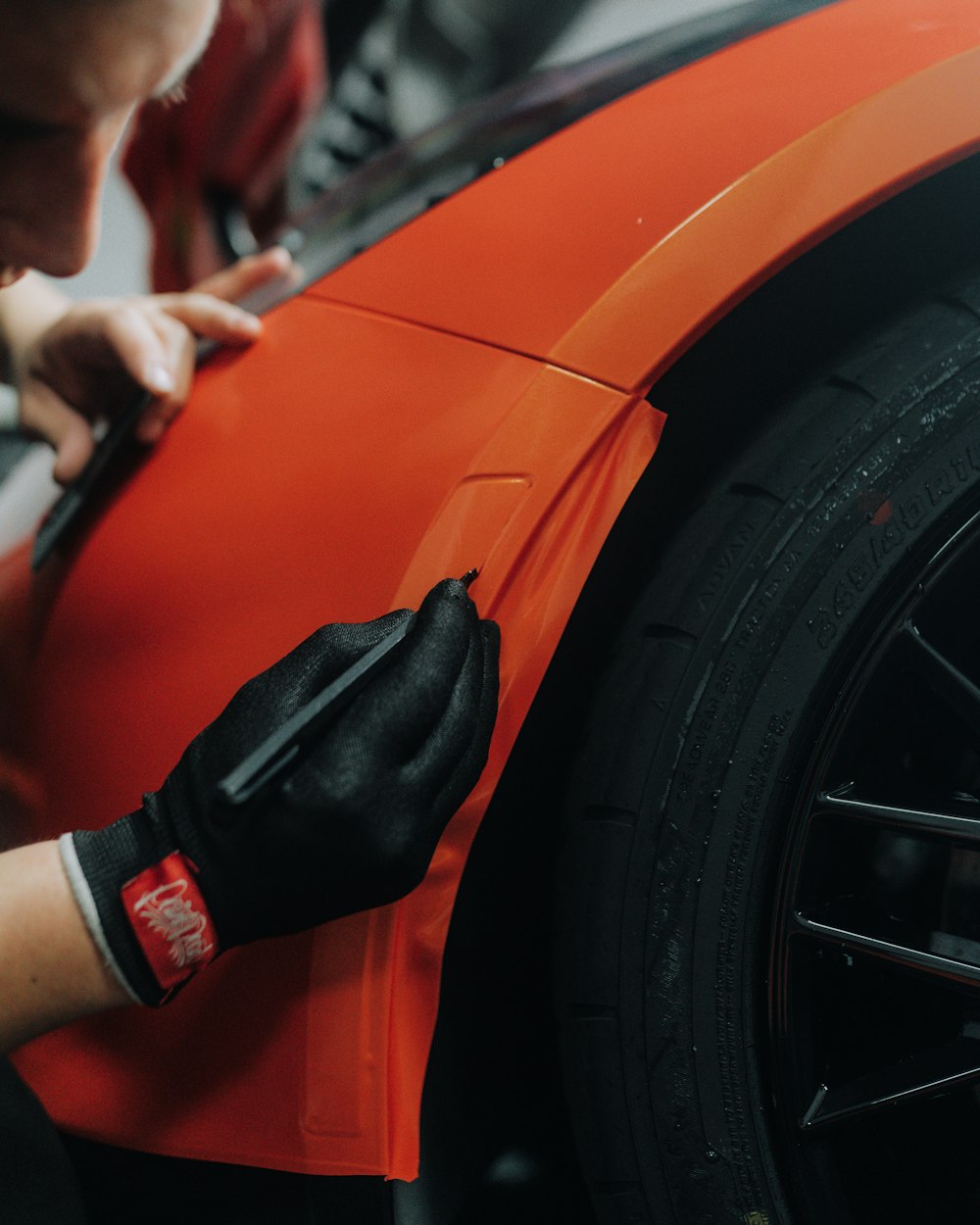 Un hombre está trabajando en un coche naranja