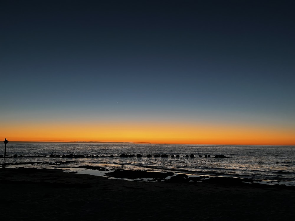 une personne debout sur une plage au coucher du soleil