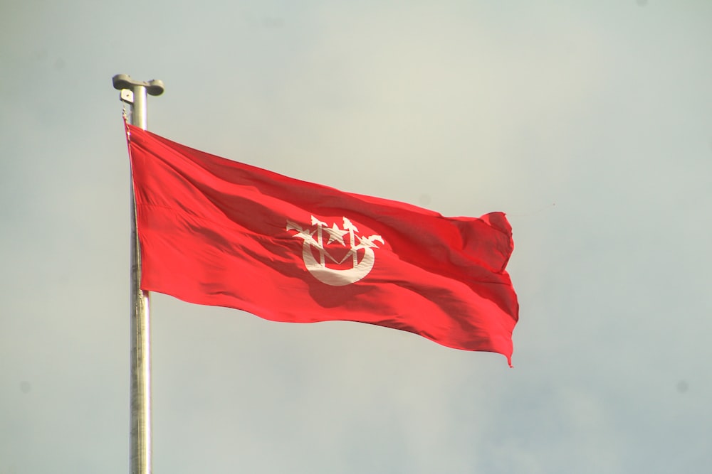 Un drapeau rouge flottant dans le vent par temps nuageux