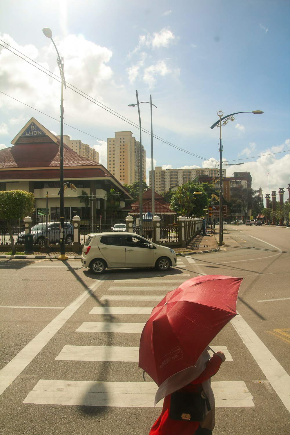 a person with a red umbrella crossing a street